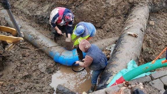 Аварийна ремонтна връзка с син фасонен елемент върху магистрален водопровод в кални условия.