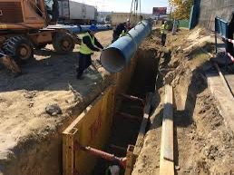 Полагане на тръба в укрепен изкоп с кофражни платна по градски коридор.